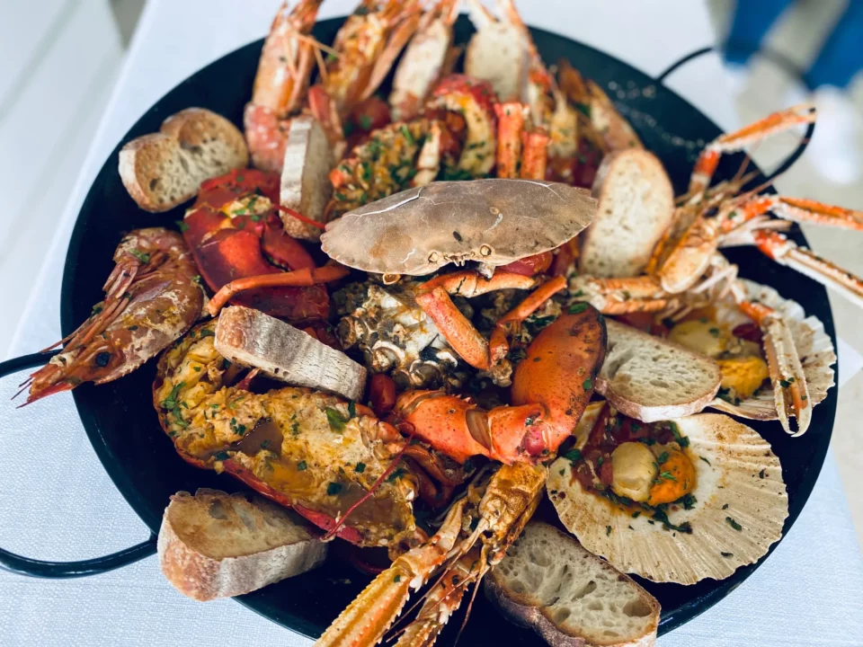 Grande padella di frutti di mare cotti del Ristorante Pizzeria Il Piacere a Modena, con astice, scampi, granchio, mazzancolle, capesante e pane tostato: un trionfo di specialità di pesce.