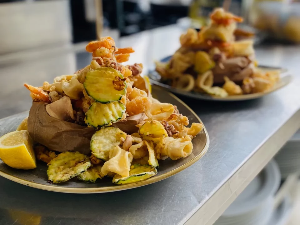 Frittura mista di pesce e verdure del Ristorante Pizzeria Il Piacere a Modena, servita con limone su piatto rustico, una delle specialità di mare del locale